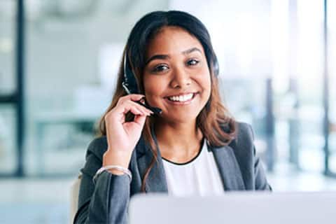 Customer support: woman smiling with headset on over a computer